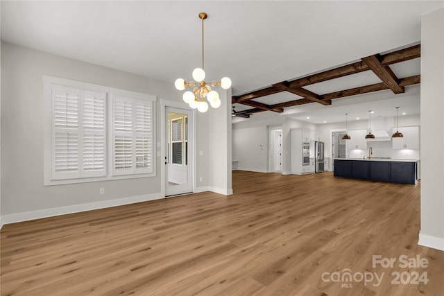 unfurnished living room with light hardwood / wood-style floors, a chandelier, coffered ceiling, and beamed ceiling