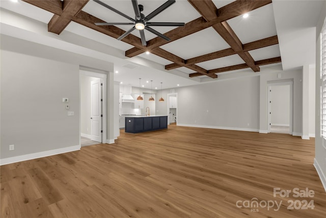 unfurnished living room with coffered ceiling, beamed ceiling, light hardwood / wood-style flooring, sink, and ceiling fan