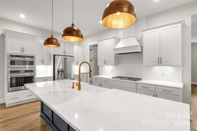 kitchen featuring sink, appliances with stainless steel finishes, pendant lighting, and light wood-type flooring