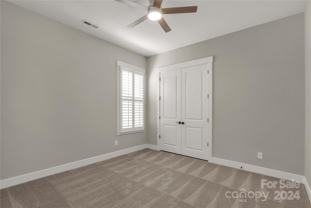 unfurnished bedroom featuring light colored carpet, a closet, and ceiling fan