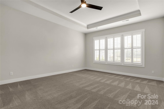 spare room featuring carpet flooring, a tray ceiling, and ceiling fan