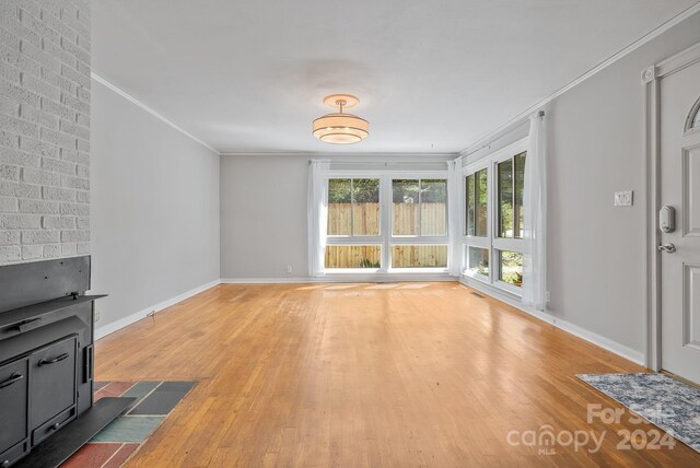 unfurnished living room with ornamental molding, hardwood / wood-style flooring, and a wood stove