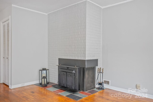 details with wood-type flooring, ornamental molding, and a wood stove