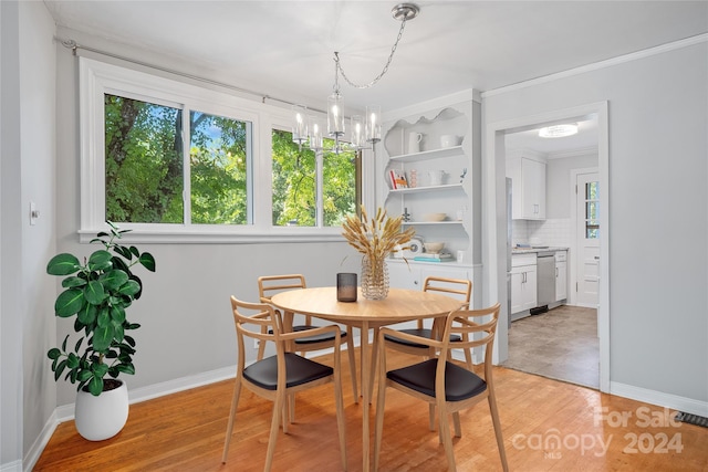 dining space with an inviting chandelier, light wood-type flooring, and crown molding