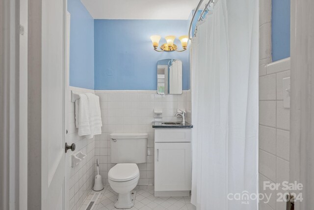 bathroom featuring toilet, vanity, tile patterned floors, and tile walls