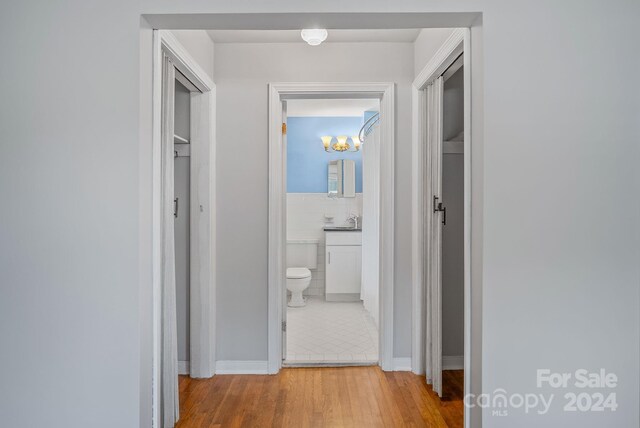 hallway featuring tile walls, sink, and light hardwood / wood-style floors