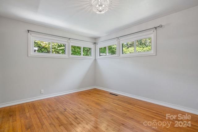 spare room with a notable chandelier and light hardwood / wood-style flooring