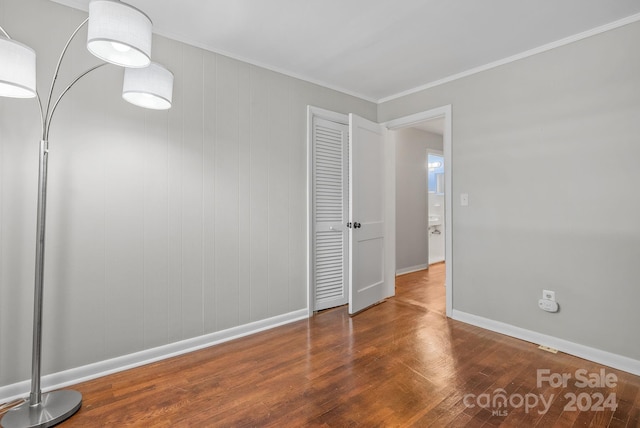 spare room with ornamental molding, wooden walls, and wood-type flooring