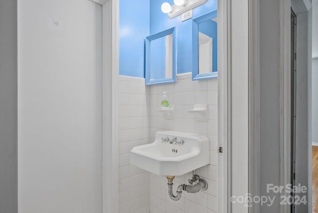 bathroom featuring sink and tile walls