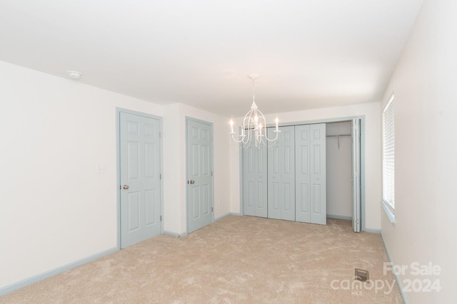 unfurnished bedroom featuring light carpet and a notable chandelier