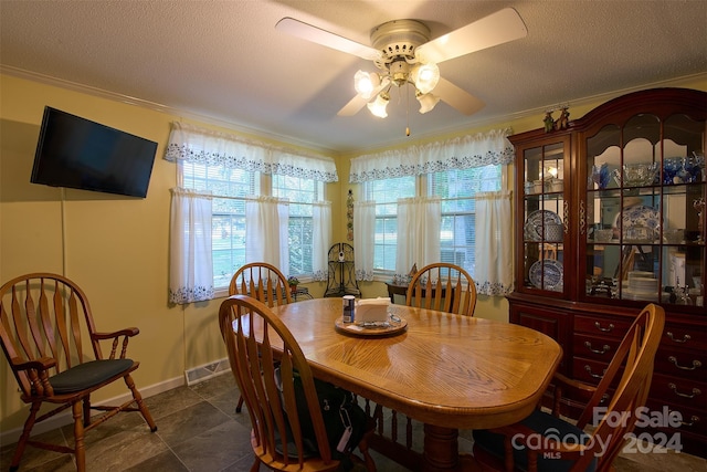 tiled dining space with a textured ceiling, ceiling fan, and ornamental molding