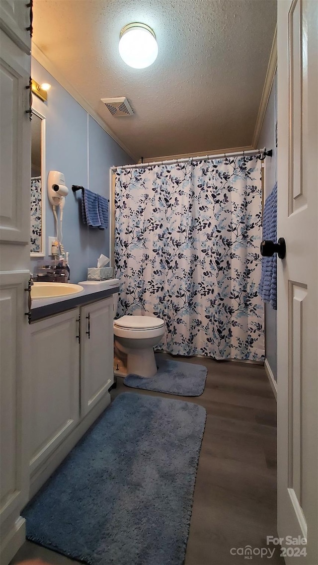 bathroom featuring crown molding, wood-type flooring, a textured ceiling, toilet, and vanity