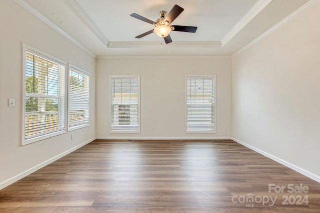 empty room featuring dark hardwood / wood-style flooring, ornamental molding, and a raised ceiling