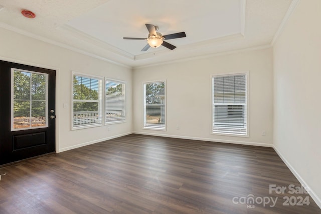 empty room featuring ceiling fan, dark hardwood / wood-style flooring, ornamental molding, and a raised ceiling