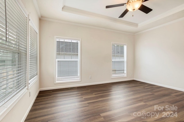 empty room featuring a raised ceiling, ceiling fan, dark hardwood / wood-style floors, and crown molding