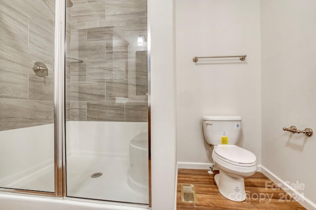 bathroom with hardwood / wood-style floors, an enclosed shower, and toilet