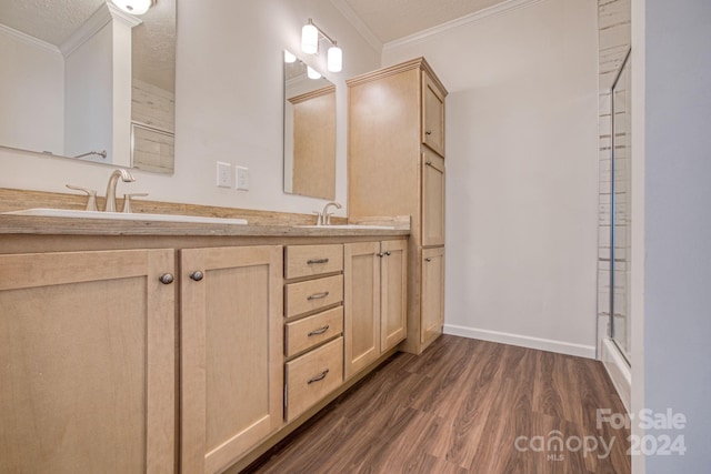 bathroom with a textured ceiling, hardwood / wood-style floors, vanity, walk in shower, and ornamental molding