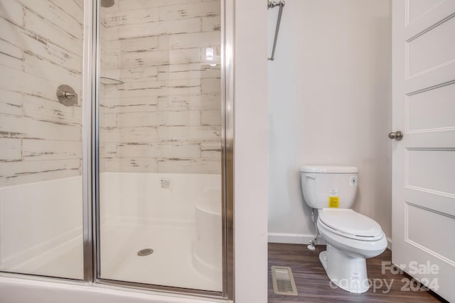 bathroom with hardwood / wood-style flooring, toilet, and walk in shower