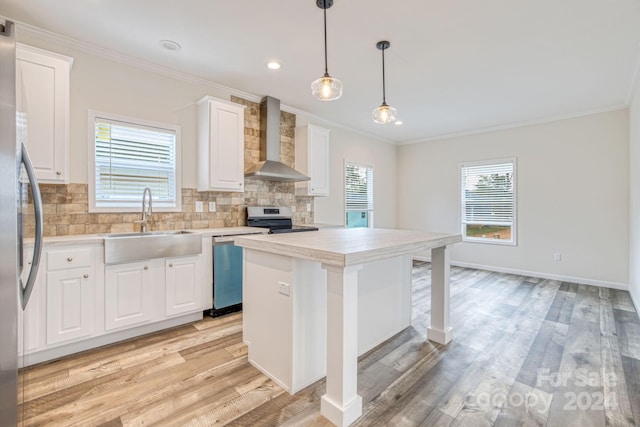 kitchen with wall chimney exhaust hood, white cabinets, light wood-type flooring, and stainless steel appliances