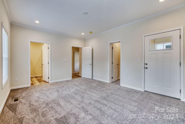 entryway featuring light colored carpet, ornamental molding, and a healthy amount of sunlight