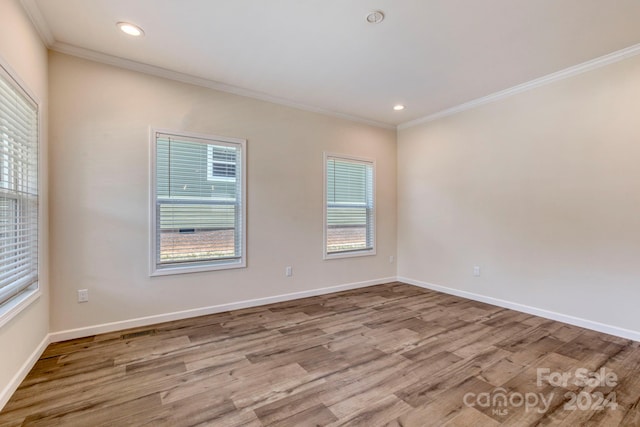 empty room featuring light wood-type flooring, ornamental molding, and a wealth of natural light