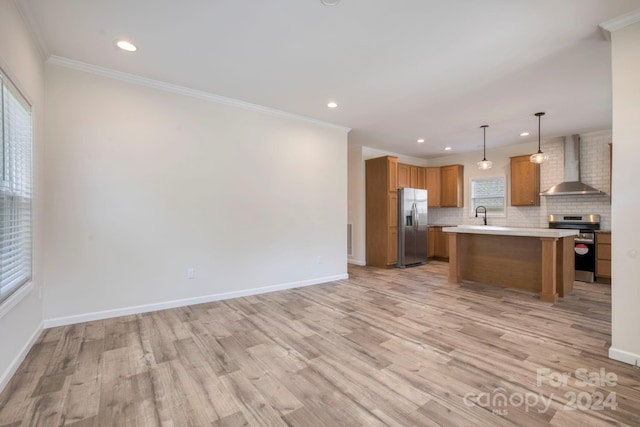 kitchen featuring pendant lighting, a kitchen island, wall chimney range hood, light hardwood / wood-style flooring, and stainless steel appliances