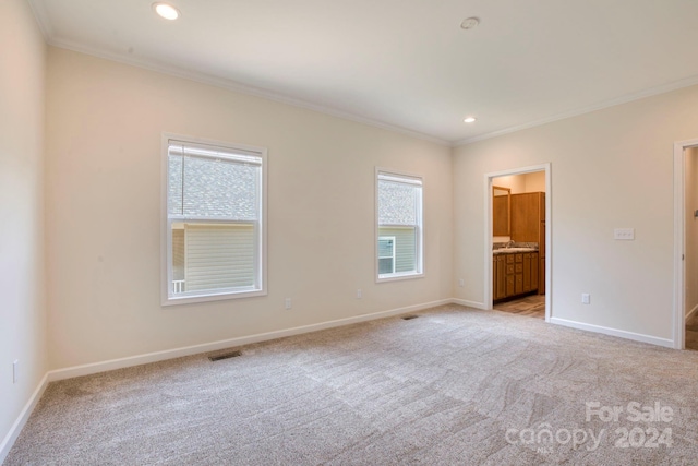 unfurnished bedroom with light carpet, multiple windows, ensuite bathroom, and crown molding