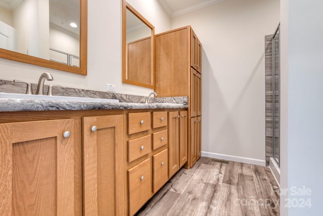 bathroom featuring wood-type flooring, walk in shower, vanity, and crown molding