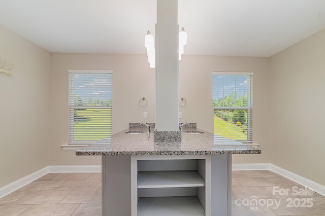 kitchen featuring kitchen peninsula, light stone countertops, light tile patterned floors, and sink