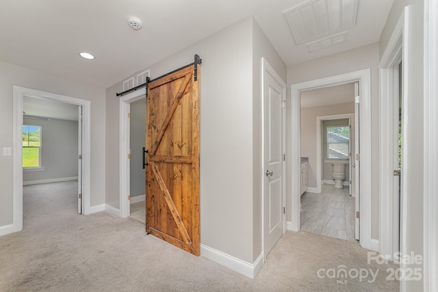 hall with light carpet and a barn door