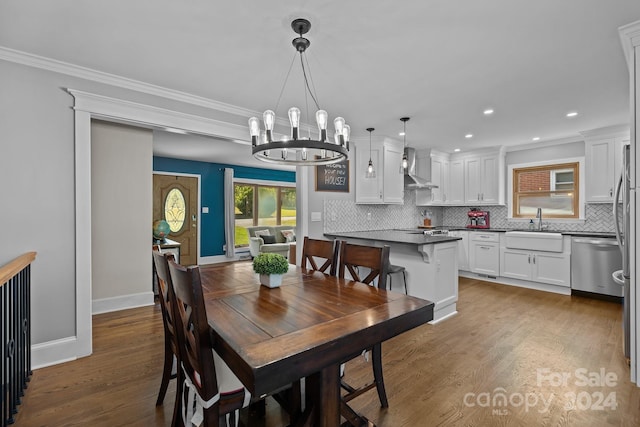 dining room featuring sink, dark hardwood / wood-style flooring, a chandelier, and ornamental molding