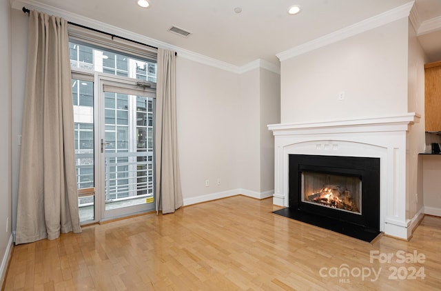 unfurnished living room featuring a healthy amount of sunlight, crown molding, and hardwood / wood-style floors