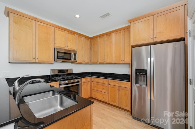 kitchen with light brown cabinets, appliances with stainless steel finishes, light hardwood / wood-style flooring, and sink