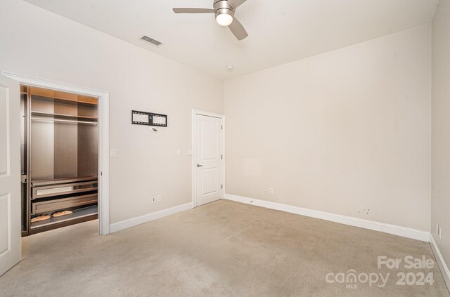 unfurnished bedroom featuring ceiling fan, light colored carpet, and a closet