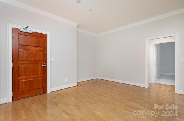 empty room featuring light wood-type flooring and crown molding