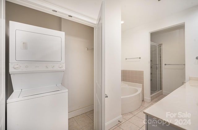 laundry area featuring stacked washer / dryer and light tile patterned floors