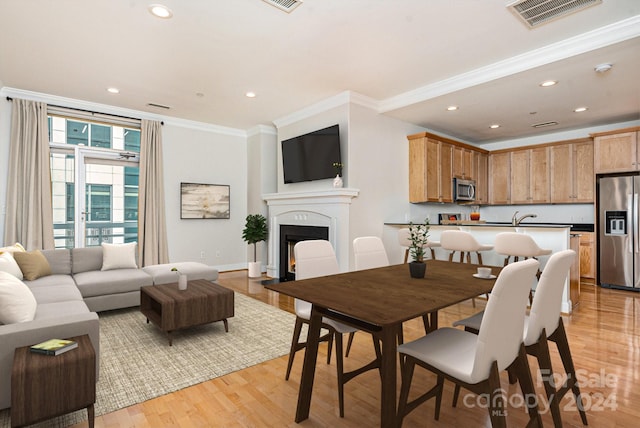 dining room featuring light wood-type flooring and crown molding