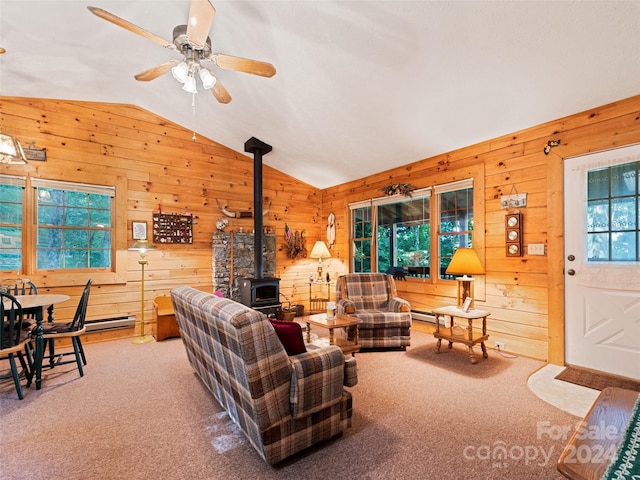 carpeted living room with lofted ceiling, ceiling fan, wood walls, a wood stove, and a baseboard radiator