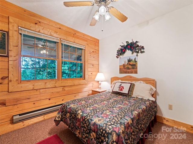 carpeted bedroom with ceiling fan, baseboard heating, and wood walls