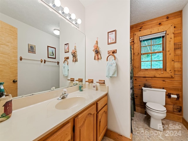 bathroom featuring toilet, wood walls, tile patterned floors, a textured ceiling, and vanity