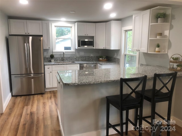 kitchen featuring a kitchen breakfast bar, white cabinetry, kitchen peninsula, and appliances with stainless steel finishes