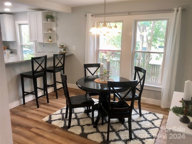 dining area featuring light wood-type flooring, an inviting chandelier, and plenty of natural light