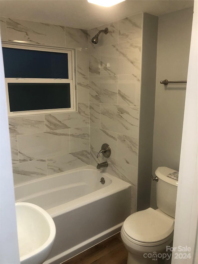 full bathroom featuring sink, toilet, wood-type flooring, and tiled shower / bath