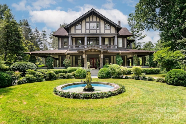 tudor house featuring a front lawn and a balcony