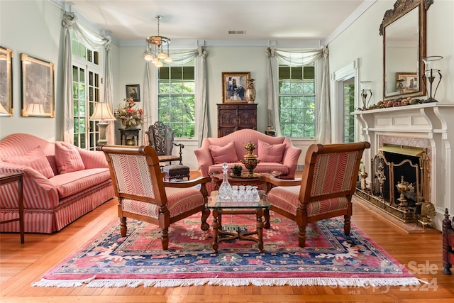 sitting room with a high end fireplace, ornamental molding, a notable chandelier, and light wood-type flooring