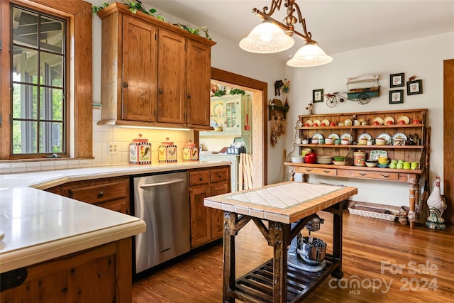 kitchen with dark hardwood / wood-style flooring, stainless steel dishwasher, backsplash, and decorative light fixtures