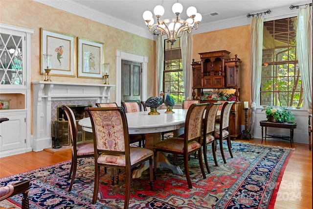 dining room featuring light hardwood / wood-style flooring, ornamental molding, a notable chandelier, and a fireplace