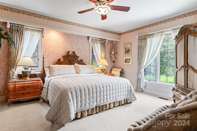 bedroom with ceiling fan, crown molding, light colored carpet, and multiple windows