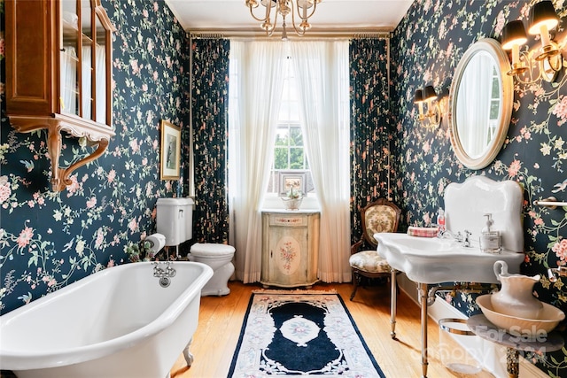 bathroom featuring toilet, wood-type flooring, and a tub to relax in