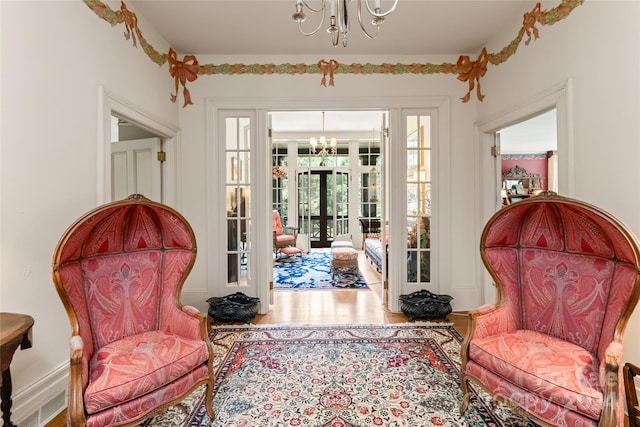 sitting room featuring hardwood / wood-style flooring, french doors, and a notable chandelier